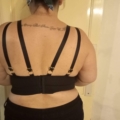 Une personne avec un tatouage dans le dos porte la Bralette Morgon, un haut à bretelles noir avec une découpe en trou de serrure dans le dos, mettant en valeur le style chic de Mode Grande Taille. Mode Grande taille