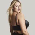 Femme aux cheveux blonds portant le Soutien gorge bandeau Dana noir, regardant par-dessus son épaule sur un fond uni. Mode Grande taille