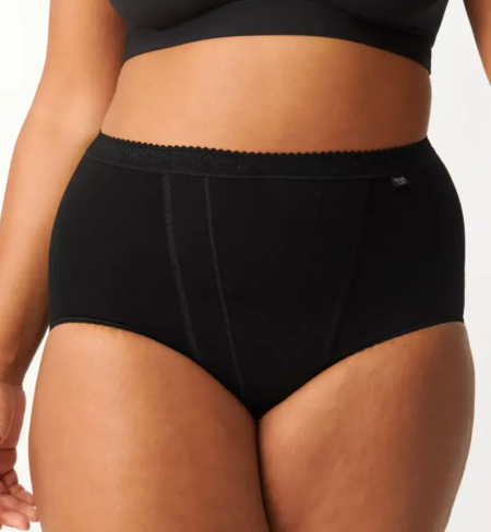 Une personne portant un lot de 2 culottes de contrôle maxi sous-vêtements taille haute noirs Sloggi et un haut noir élégant, mettant en valeur la partie médiane et le bas du corps. Mode Grande taille