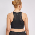 Une personne aux cheveux blonds coiffés en chignon porte la brassière Top zero feel bliss de Sloggi et les sous-vêtements assortis en dentelle noire, vue de dos. Cet ensemble chic est parfait pour les adeptes de la mode Grande Taille qui cherchent à faire sensation. Mode Grande taille