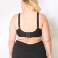 Vue arrière d'une femme aux cheveux blonds portant le Soutien-gorge à agrafes et un pantalon noir, debout sur un fond blanc. Mode Grande taille