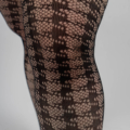 Gros plan de jambes portant des collants résille à motifs noirs avec un design à rayures verticales. Mode Grande taille