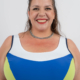 Femme souriante portant un maillot de bain bleu et blanc avec un collier ras du cou, debout devant un fond uni. Mode Grande taille