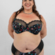 Une femme souriante en lingerie à motifs étoilés pose sur un fond blanc uni. Mode Grande taille