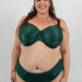 Une femme souriante portant un soutien-gorge et une culotte verts pose sur un fond blanc uni. Mode Grande taille