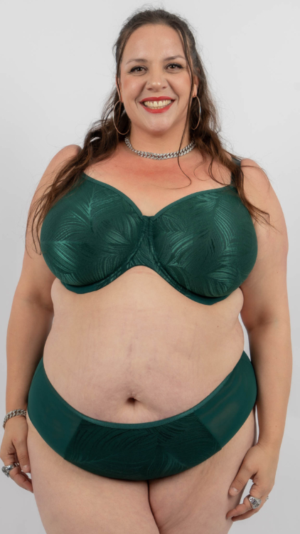 Une femme souriante portant un soutien-gorge et une culotte verts pose sur un fond blanc uni. Mode Grande taille