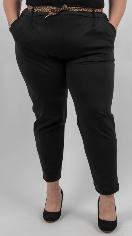 Personne portant un pantalon noir avec les mains dans les poches, une ceinture à imprimé léopard et des talons noirs, sur fond blanc. Mode Grande taille