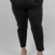 Personne portant un pantalon noir avec les mains dans les poches, une ceinture à imprimé léopard et des talons noirs, sur fond blanc. Mode Grande taille