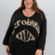 Une femme souriante portant un pull noir avec un motif de croissant et le mot « croissant » écrit dessus. Mode Grande taille