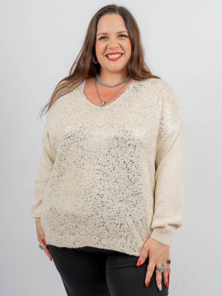 Femme souriante aux longs cheveux bruns portant un pull de couleur crème avec un motif scintillant et un pantalon noir. Mode Grande taille