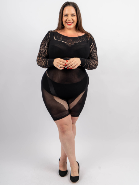 Une femme portant un haut noir en dentelle et un short noir assorti, debout et souriant, les mains jointes. Mode Grande taille