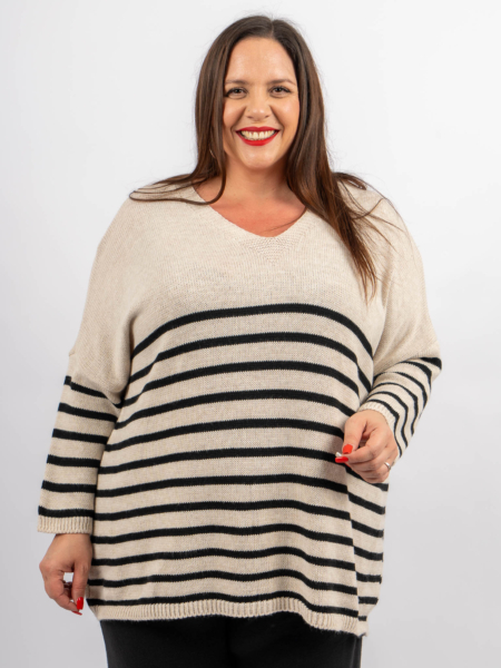 Femme souriante dans un pull rayé avec des lignes horizontales noires et blanches, debout sur un fond uni. Mode Grande taille