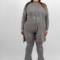 Femme souriante, portant une tenue en tricot gris assortie et des talons noirs sur fond blanc. Mode Grande taille