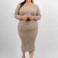 Femme souriante dans une robe en tricot côtelé beige et des chaussures noires, debout sur un fond blanc. Mode Grande taille