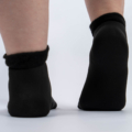 Gros plan d'une personne portant des chaussettes noires avec des revers en fourrure, montrée de dos sur un fond blanc. Mode Grande taille