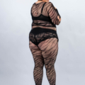 Personne souriante, portant une tenue en dentelle noire transparente et des talons noirs, debout sur un fond uni. Mode Grande taille