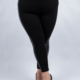 Personne portant des leggings noirs avec une bande latérale brillante et des chaussures noires sur un fond gris. Mode Grande taille