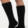 Une personne portant des « Chaussettes hautes à bords larges doublure polaire » noires à bords festonnés sur fond blanc. Mode Grande taille