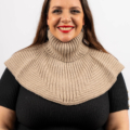 Femme souriante portant une cape en tricot côtelé beige à col haut et un haut noir. Mode Grande taille