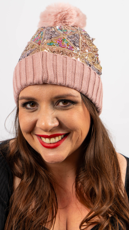 Femme souriante, portant un bonnet rose à paillettes et pompon, et un haut noir. Mode Grande taille