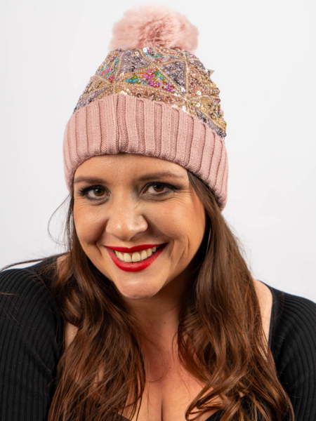 Femme souriante, portant un bonnet rose à paillettes et pompon, et un haut noir. Mode Grande taille