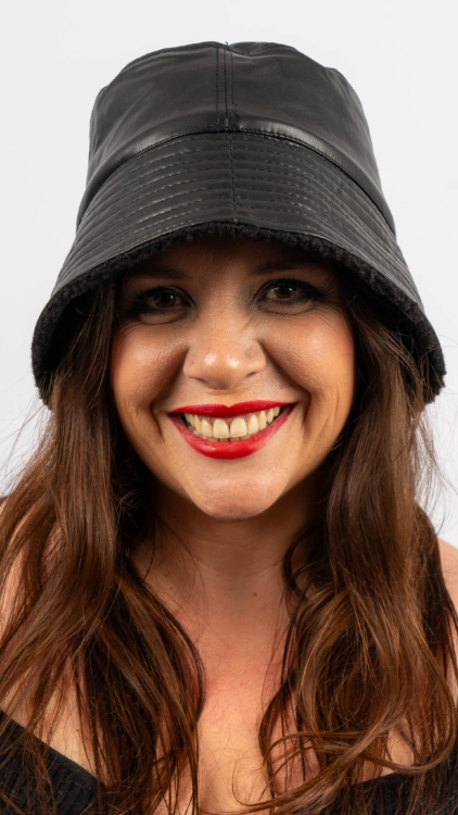 Femme souriante aux longs cheveux bruns portant un chapeau en cuir noir et du rouge à lèvres rouge. Mode Grande taille