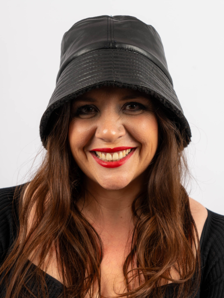 Femme souriante aux longs cheveux bruns portant un chapeau en cuir noir et du rouge à lèvres rouge. Mode Grande taille