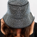 Personne portant un chapeau seau étincelant parsemé de strass, regardant vers le bas ; visage non visible. Mode Grande taille