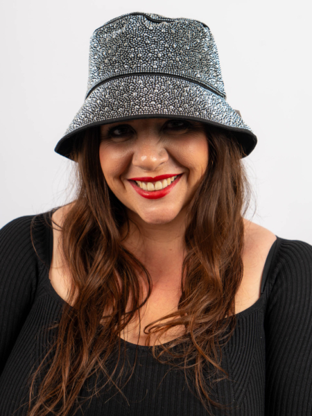 Femme avec un chapeau à motifs et du rouge à lèvres rouge, souriant sur un fond blanc uni. Mode Grande taille