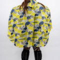 Personne portant un poncho à motifs jaune et bleu avec des bottes noires, dos à la caméra sur un fond blanc. Mode Grande taille