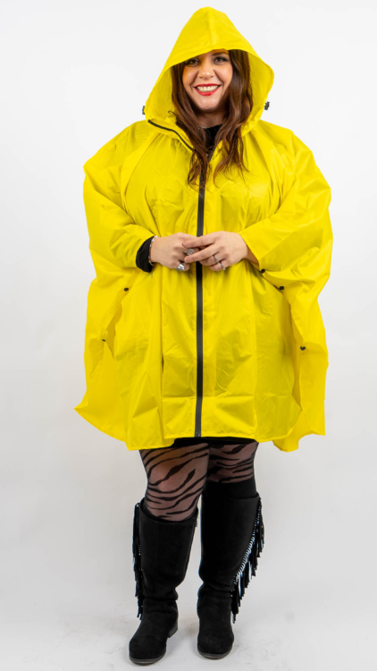 Personne portant un imperméable jaune vif, des bottes noires et des collants à motifs, souriant sur un fond uni. Mode Grande taille