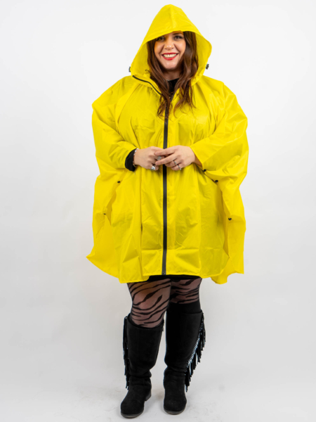 Personne portant un imperméable jaune vif, des bottes noires et des collants à motifs, souriant sur un fond uni. Mode Grande taille