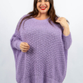 Femme souriante dans un pull lavande le tenant doucement, avec un fond blanc. Mode Grande taille