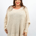 Une personne portant un pull en tricot beige sourit sur un fond uni. Mode Grande taille