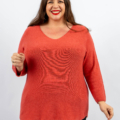 Femme en pull rouge souriant sur fond blanc. Mode Grande taille