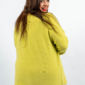 Femme portant un pull jaune vif, souriant et regardant par-dessus son épaule sur un fond uni. Mode Grande taille