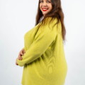 Femme souriante dans un pull jaune debout sur un fond blanc uni. Mode Grande taille