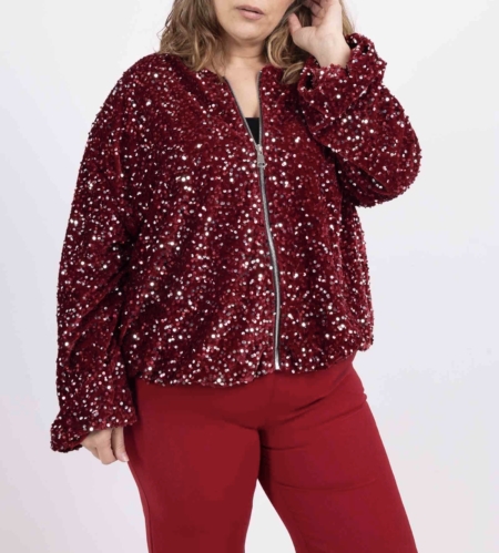 Une personne portant une veste Bomber en velours bordeaux à paillettes et un pantalon rouge assorti se tient debout sur un fond uni. Mode Grande taille