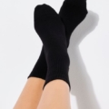 Une personne portant des chaussettes noires 'Chausettes message et coeur rouge', les jambes croisées, sur un fond clair. Mode Grande taille