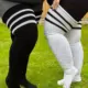 Gros plan de deux personnes portant des Chaussettes hautes jusqu'aux cuisses à rayures noires et blanches, debout sur l'herbe. Mode Grande taille