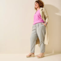 Femme en chemise rose, manteau beige, pantalon gris et Sandales compensées pieds larges Vic - Gabylou se tient debout souriante sur un fond clair. Mode Grande taille