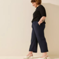 Personne debout de côté avec les mains dans les poches, portant un pull noir, un pantalon bleu marine et des Sandales à talons pieds larges LEA - Gabylou. Mode Grande taille