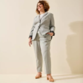 Une femme en tailleur gris clair et sandales à talons pieds larges beiges LEA - Gabylou se tient debout, souriante, sur un fond neutre. Mode Grande taille
