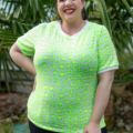 Une personne portant une chemise à motifs vert vif sourit devant des plantes tropicales. Mode Grande taille
