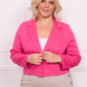 Une femme portant le Blazer court en rose avec un pantalon beige se tient contre un mur blanc, souriant à la caméra. Mode Grande taille