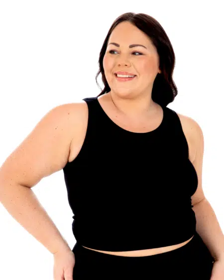 Femme souriante portant un Débardeur côtelé noir, debout sur un fond blanc. Mode Grande taille