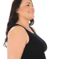 Femme aux longs cheveux noirs souriant de profil, portant un débardeur noir Débardeur côtelé sur fond blanc. Mode Grande taille