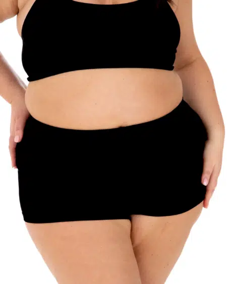 Femme grande taille portant le Boxer côtelé en noir avec un soutien-gorge assorti, posant avec la main sur la hanche sur fond blanc. Mode Grande taille