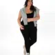 Femme souriante marchant avec assurance en Legging côtelé, tenue noire, sweat-shirt gris sur les épaules, casquette bleue et baskets blanches. Mode Grande taille