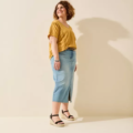 Une femme vêtue d'un haut jaune et d'une jupe en jean se tient debout, souriante, sur un fond beige, mettant en valeur les Sandales compensées pieds larges Vic - Gabylou. Mode Grande taille